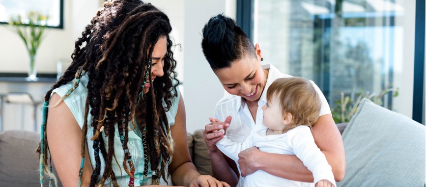 two mothers with their baby laughing